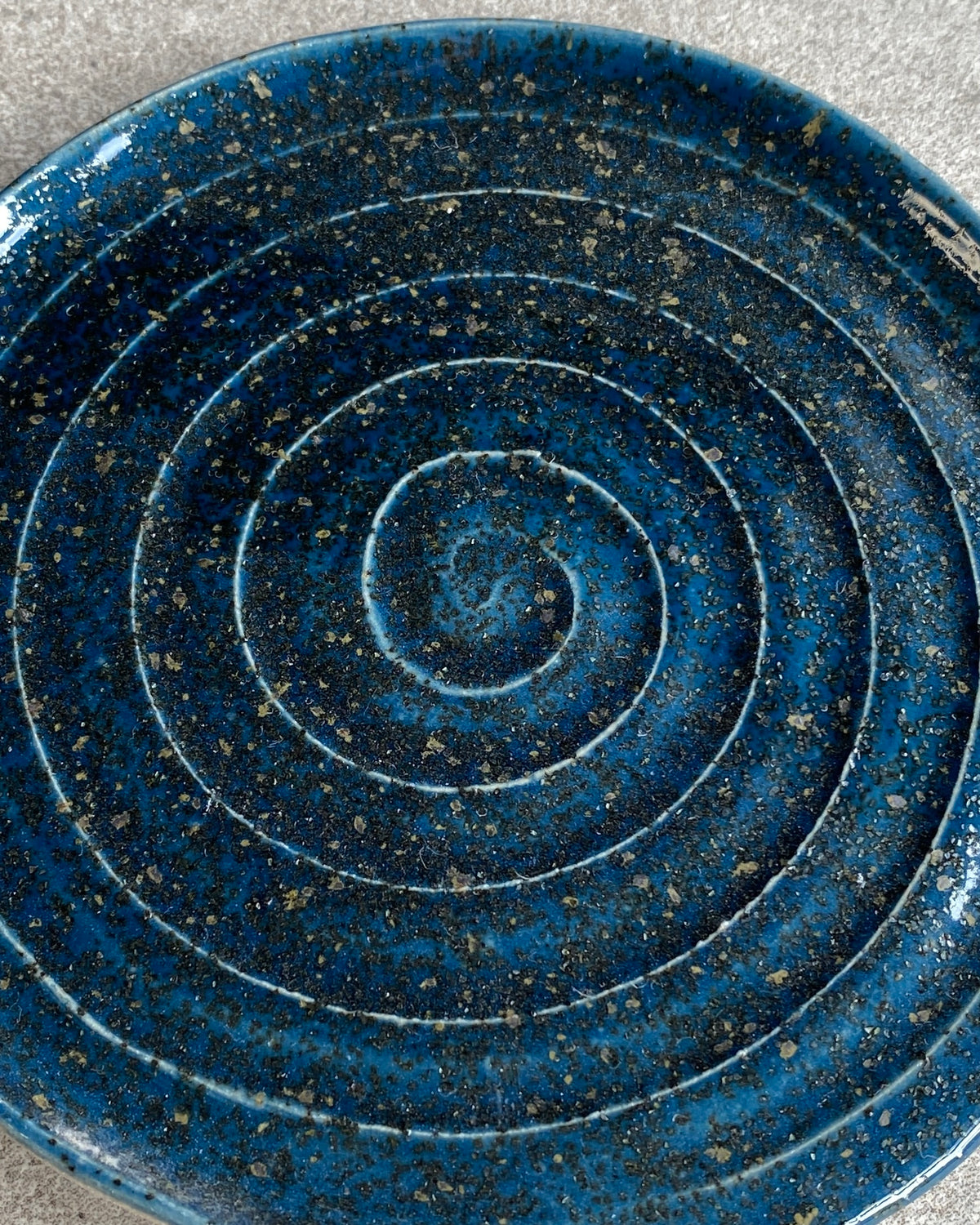 Nærbillede af spiral i mørkeblå glasur med lyse prikker