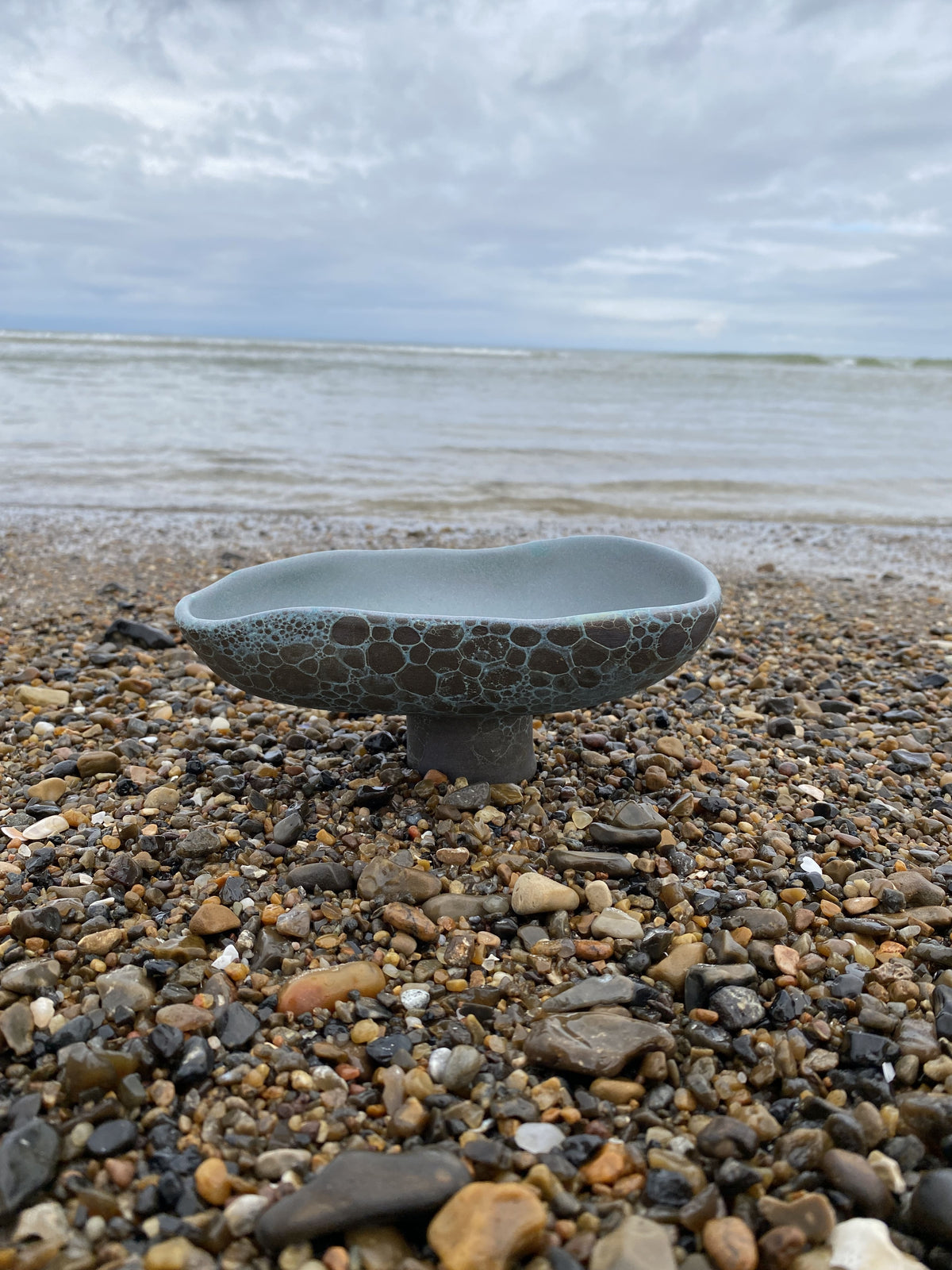 Aflang skål Blue Velvet på fod på stenstrand ved havet – håndlavet keramik fra Keramikbyh