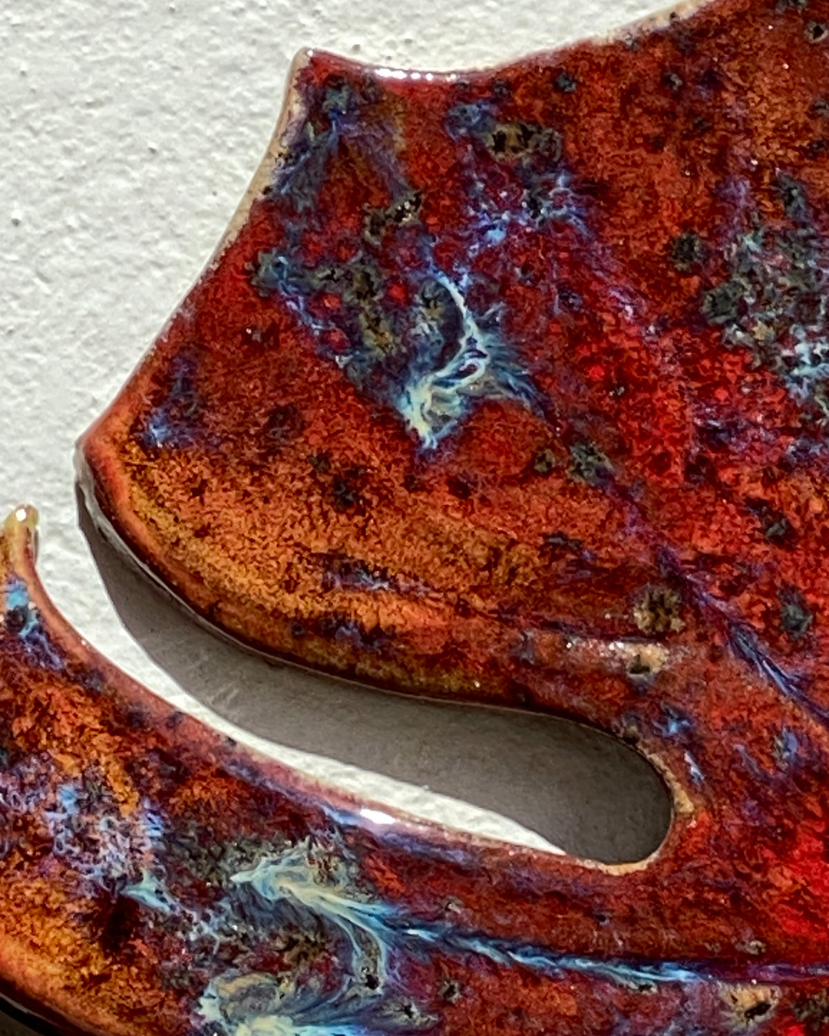 Detalje af rød, orange og blå glasur på Autumn Leaf